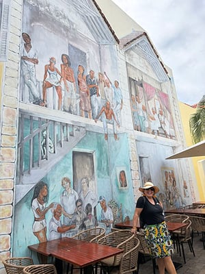 Curacaoan woman with straw hat standing in front of a mural