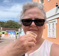 Susan with sunglasses on eating ice cream from a cup